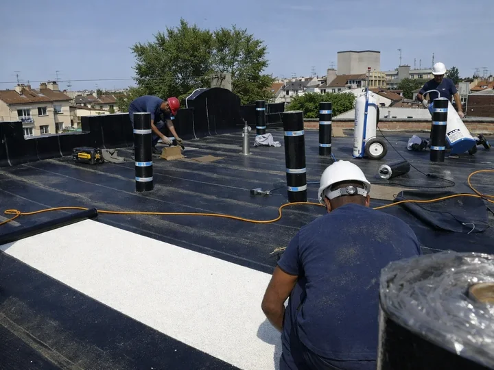 Étancheurs de France Pro Étanchéité au travail sur un toit terrasse, rouleaux de membrane et toits de Paris