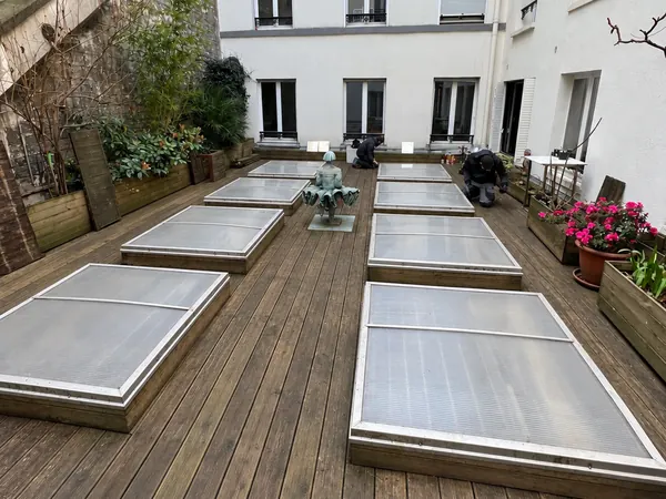 Série de lanterneaux intégrés à la terrasse en bois d'une cour d'immeuble à Paris 12e