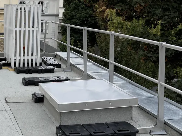 Skydome posé sur une costière relevée au bord de la toiture-terrasse d'un immeuble à Paris 8e, avec garde-corps et dalles sur plots