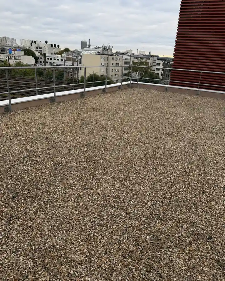 Toit terrasse sous gravillons d'un immeuble parisien, garde-corps et toits de Paris en arrière-plan