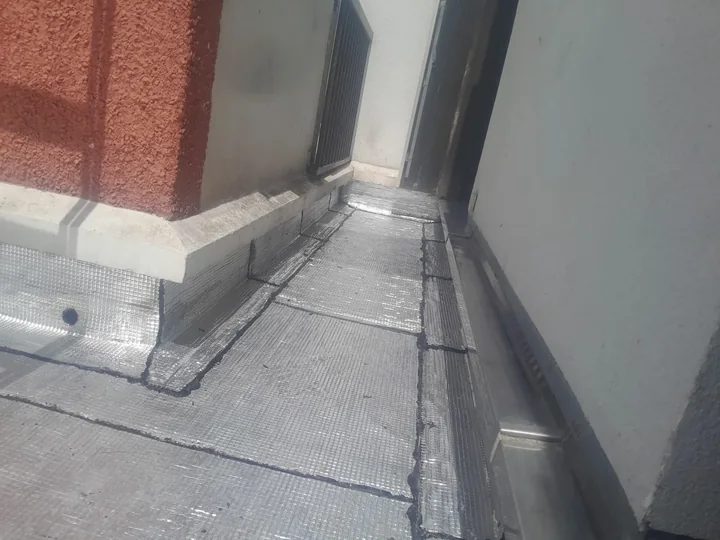 Relevés et seuil de porte-fenêtre traités en résine d'étanchéité sur un balcon à Paris 16e