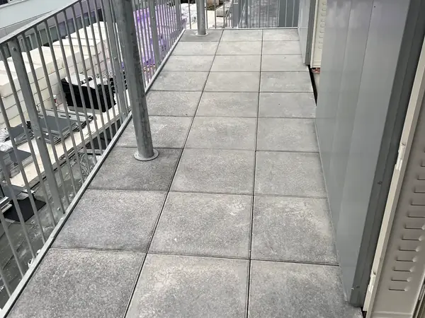 Terrasse en dalles sur plots réglables avec garde-corps, immeubles en arrière-plan
