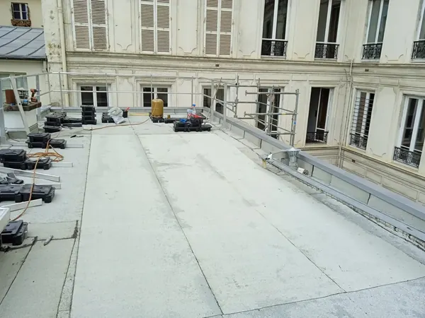Toit terrasse d'un immeuble à Paris 8e, membrane posée et plots à répartir, façade haussmannienne