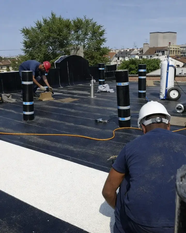Équipe d'étancheurs de France Pro Étanchéité au travail sur un toit terrasse, rouleaux de membrane et toits de Paris