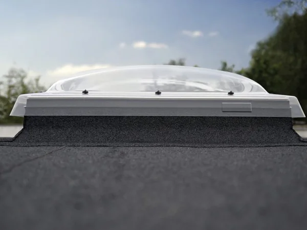 Coupole VELUX transparente posée sur un toit plat, raccordée à la membrane d'étanchéité
