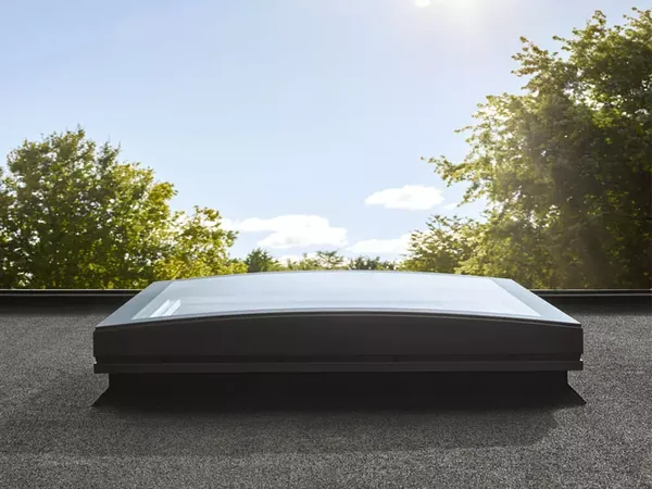 Fenêtre VELUX à verre courbé posée sur un toit plat en gravillons, vue depuis la terrasse