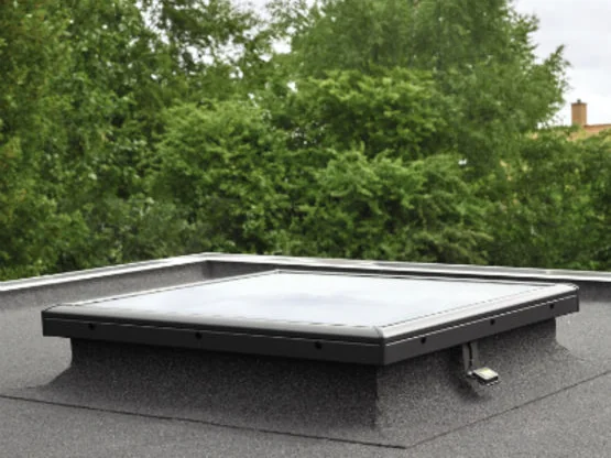 Fenêtre VELUX à vitrage plan posée sur sa costière, sur la toiture-terrasse d'une maison