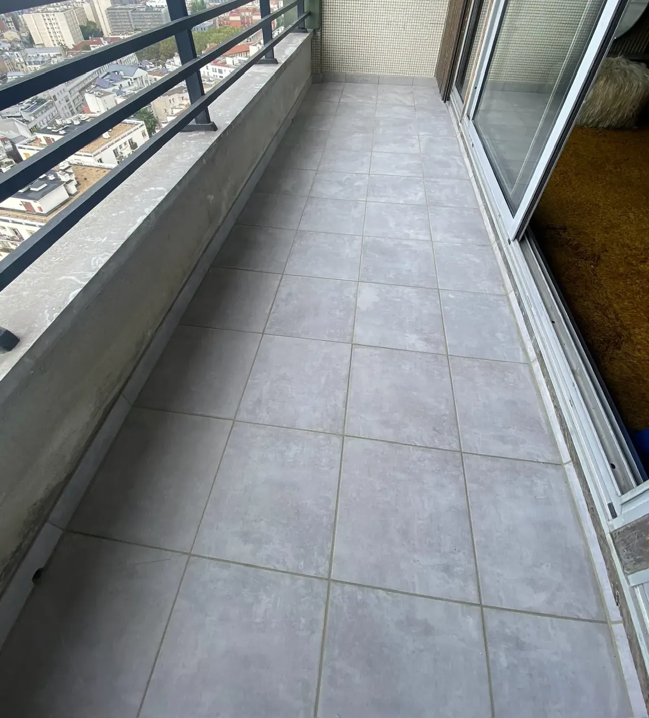 Balcon carrelé d'un appartement en étage à Paris, vue sur les toits