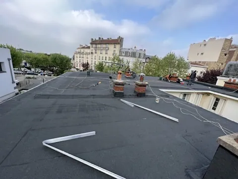 Toit terrasse d'immeuble parisien couvert d'une membrane bitume, souches de cheminée en maçonnerie