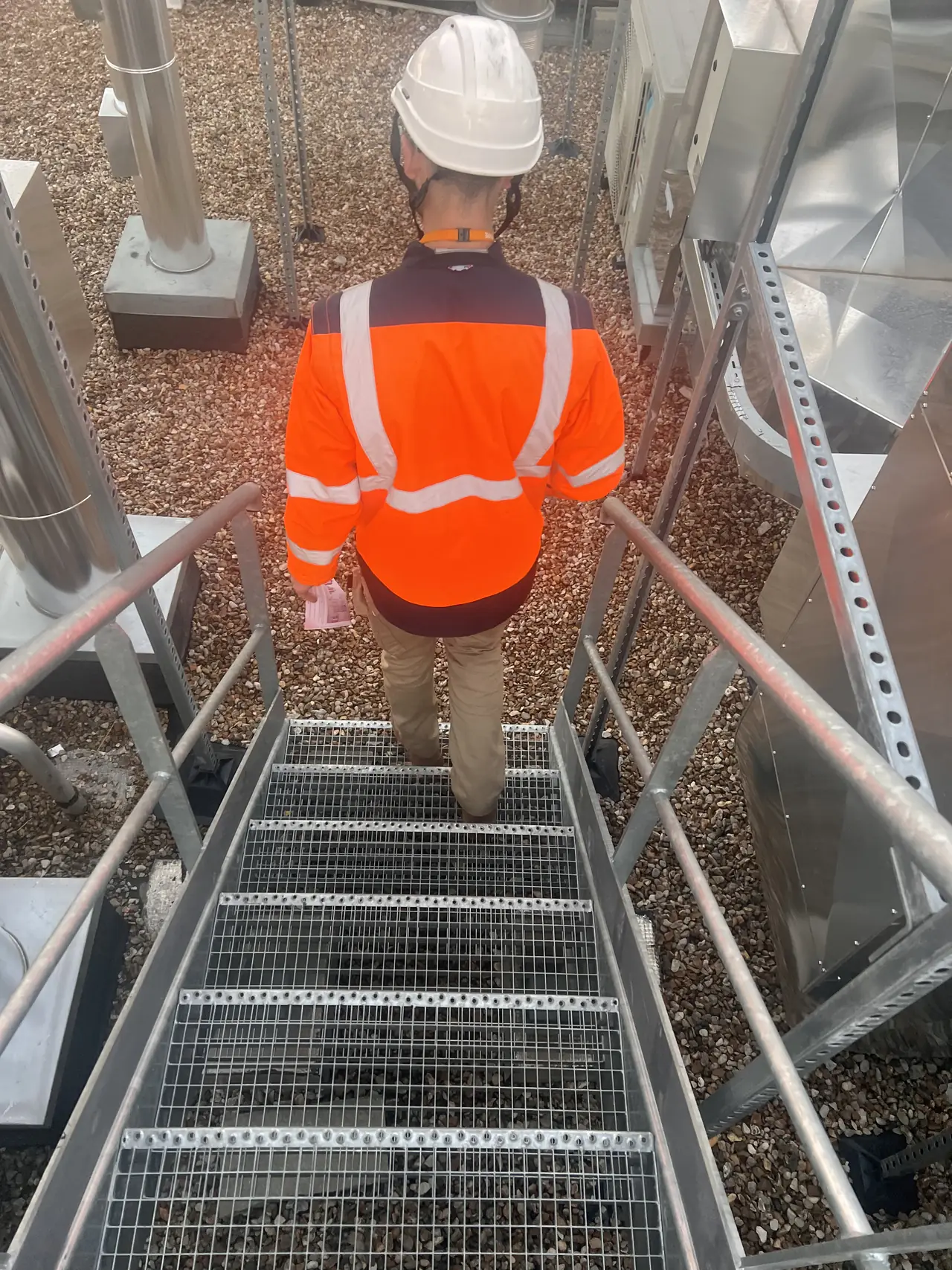 Technicien de France Pro Étanchéité montant sur un toit terrasse gravillonné à Paris au début de la journée de chantier