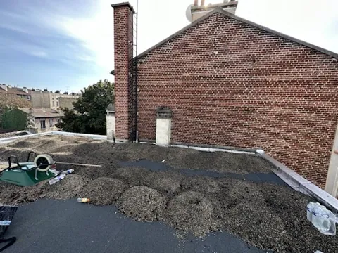 Gravillon repoussé sur un toit terrasse parisien, membrane d'étanchéité mise à nu avant travaux